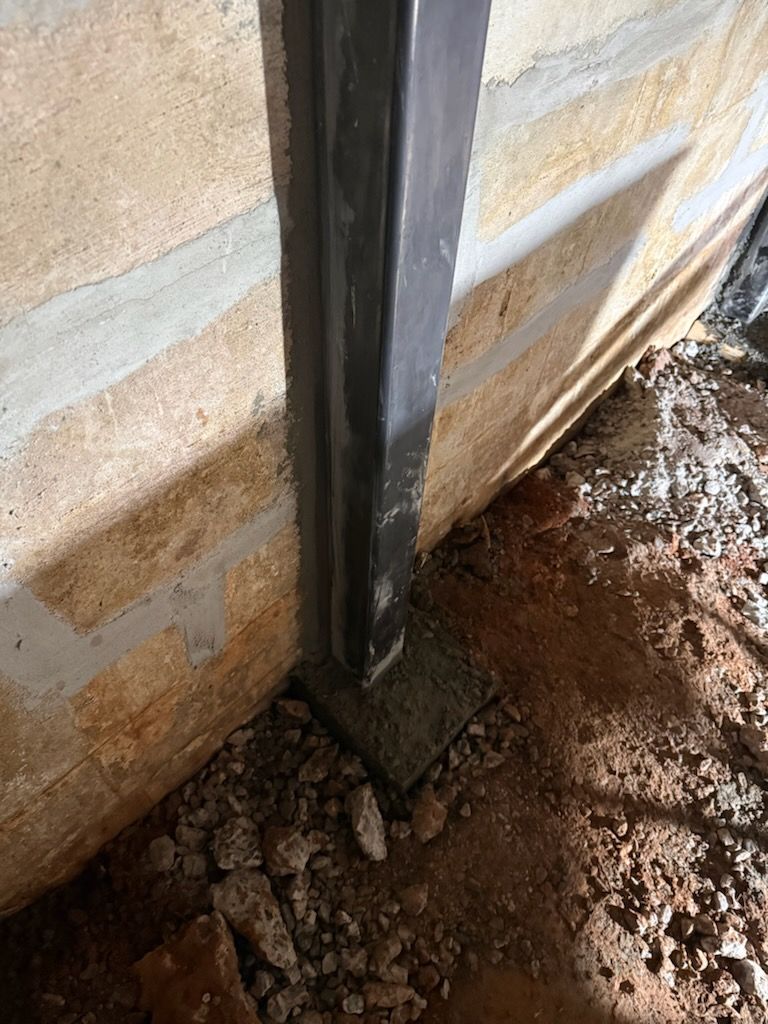 Steel wall beam base at a block basement wall