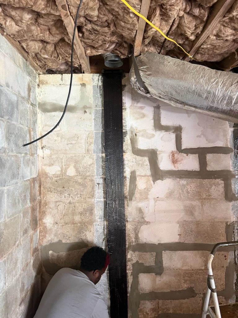 Foundation Worx installer applying carbon-fiber reinforcement to a concrete block wall