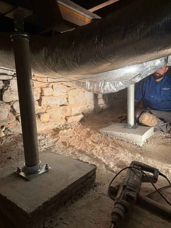 Steel support posts on new concrete footing pads in a crawl space