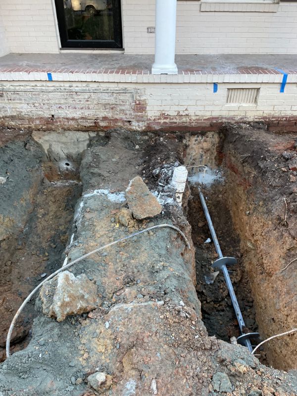 Helical pier installed in an excavation beside a front porch foundation