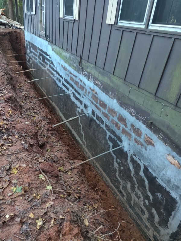 Helical tieback rods extending from an excavated block foundation wall
